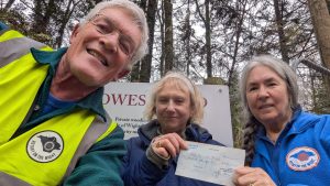 Members of Ryde Rotary Club presenting a £200 cheque donation to the Isle of Wight Red Squirrel Trust in woodland, supporting conservation work.